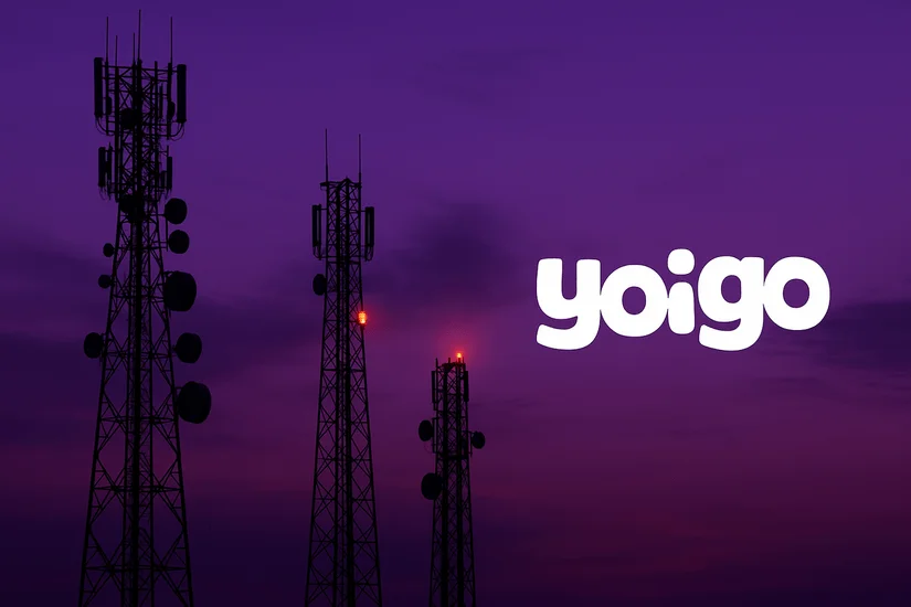 Antenas de telecomunicaciones apagándose al atardecer con el logotipo de Yoigo en primer plano.